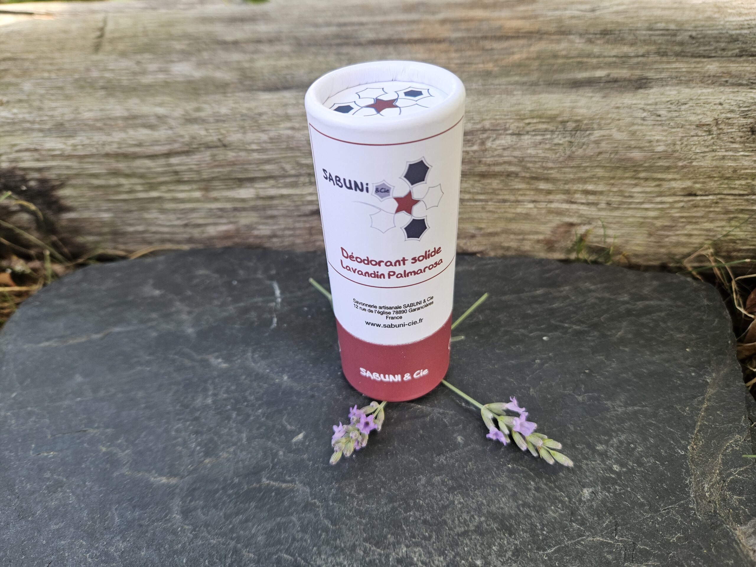 Tube du déodorant (Lavandin et palmarosa) de Sabuni & Cie, posé sur une ardoise, avec des fleurs de lavandin.