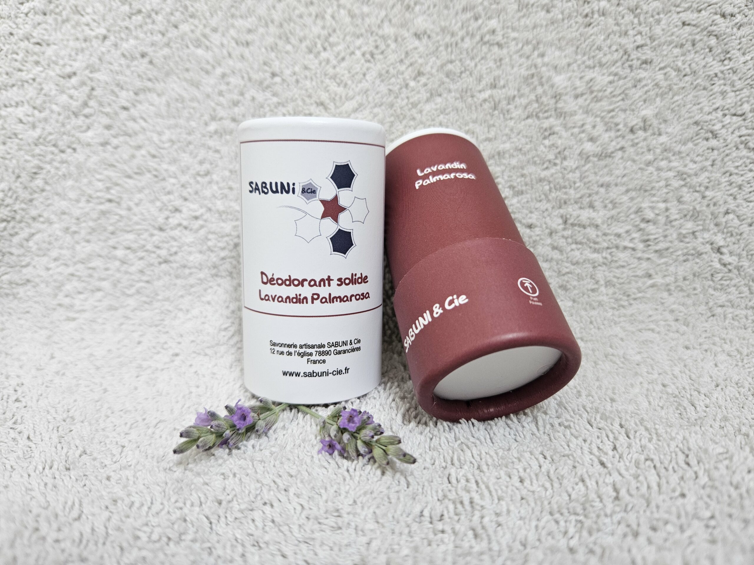 Tube du déodorant (Lavandin et palmarosa) de Sabuni & Cie, posé sur une serviette, le dessous du tube en carton est visible.