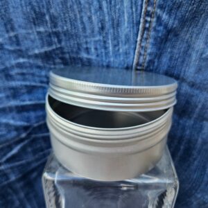 Accessoire zéro déchet de la savonnerie artisanale Sabuni & Cie. Boite ronde en aluminium. Fait en France. Dentifrice sur fond bleu jeans. Grand modèle