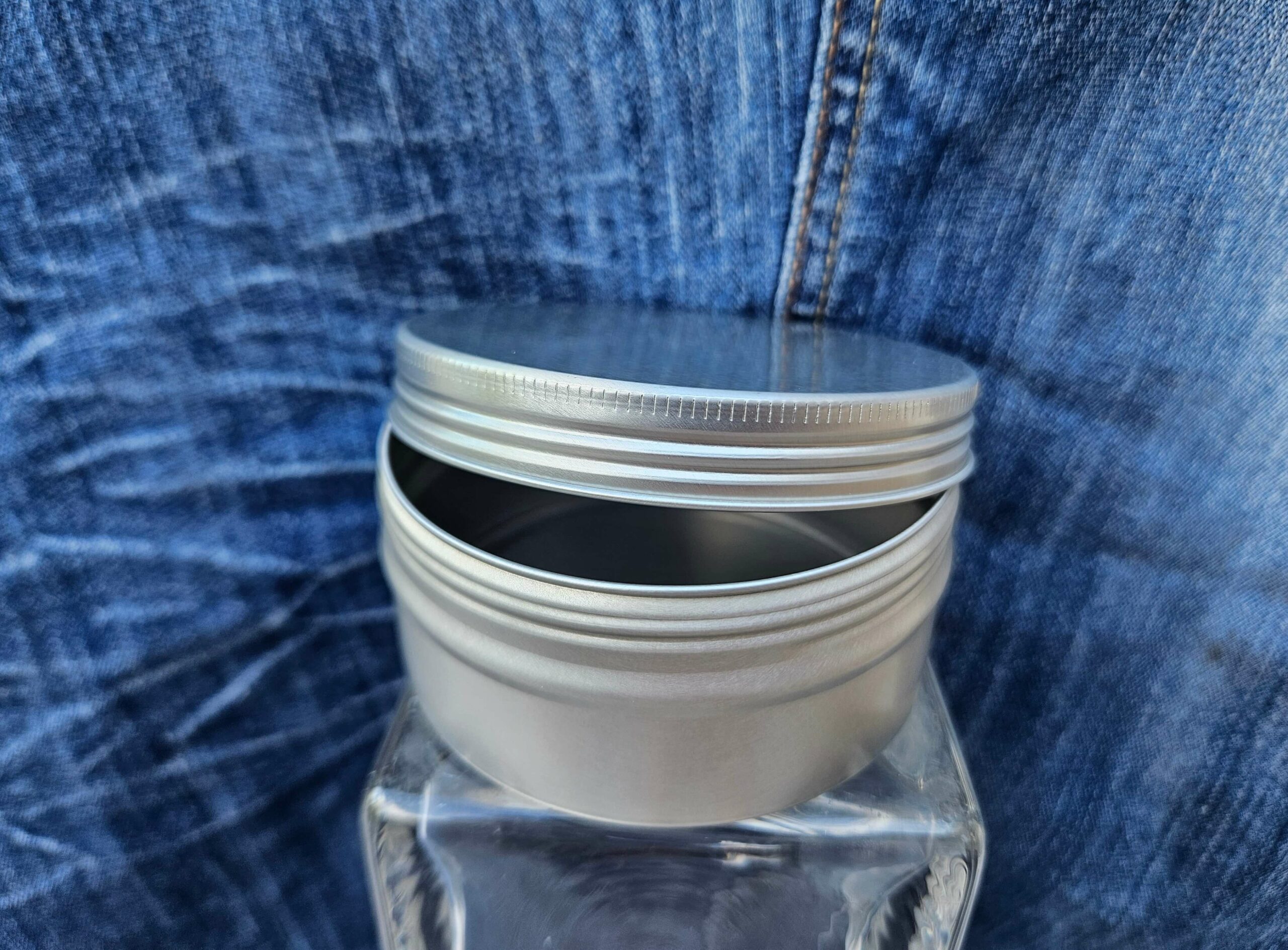 Accessoire zéro déchet de la savonnerie artisanale Sabuni & Cie. Boite ronde en aluminium. Fait en France. Dentifrice sur fond bleu jeans. Grand modèle