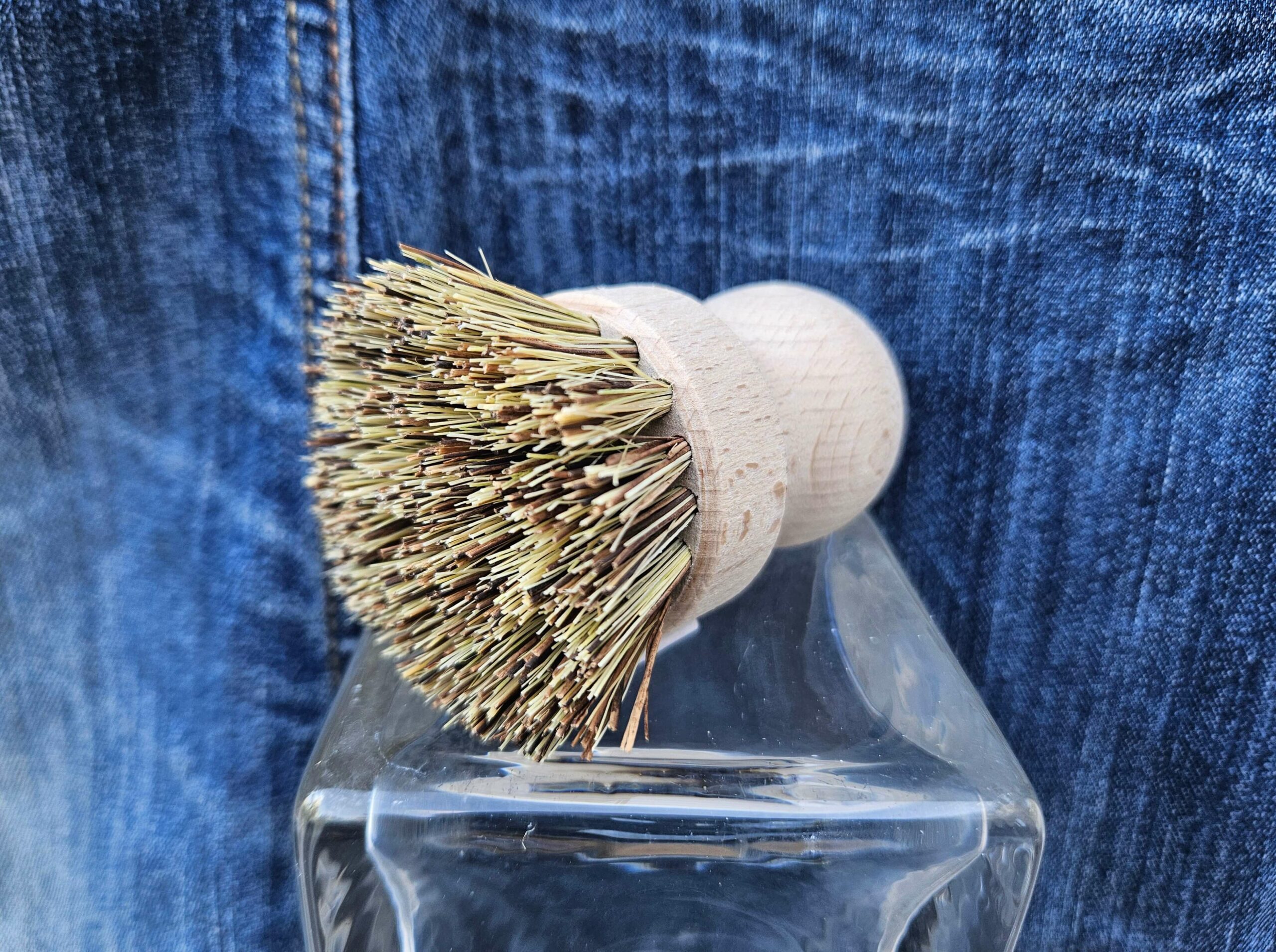 Accessoire zéro déchet de la savonnerie artisanale Sabuni & Cie. Brosse vaisselle fabriquée en Europe. Brosse vaisselle sur fond bleu jeans.