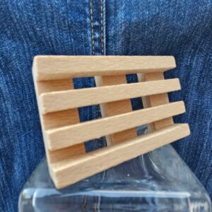 Accessoire zéro déchet de la savonnerie artisanale Sabuni & Cie. Porte savon artisanal en bois massif des Voges et d’Alsace. Porte savon en bois sur fond bleu jeans.