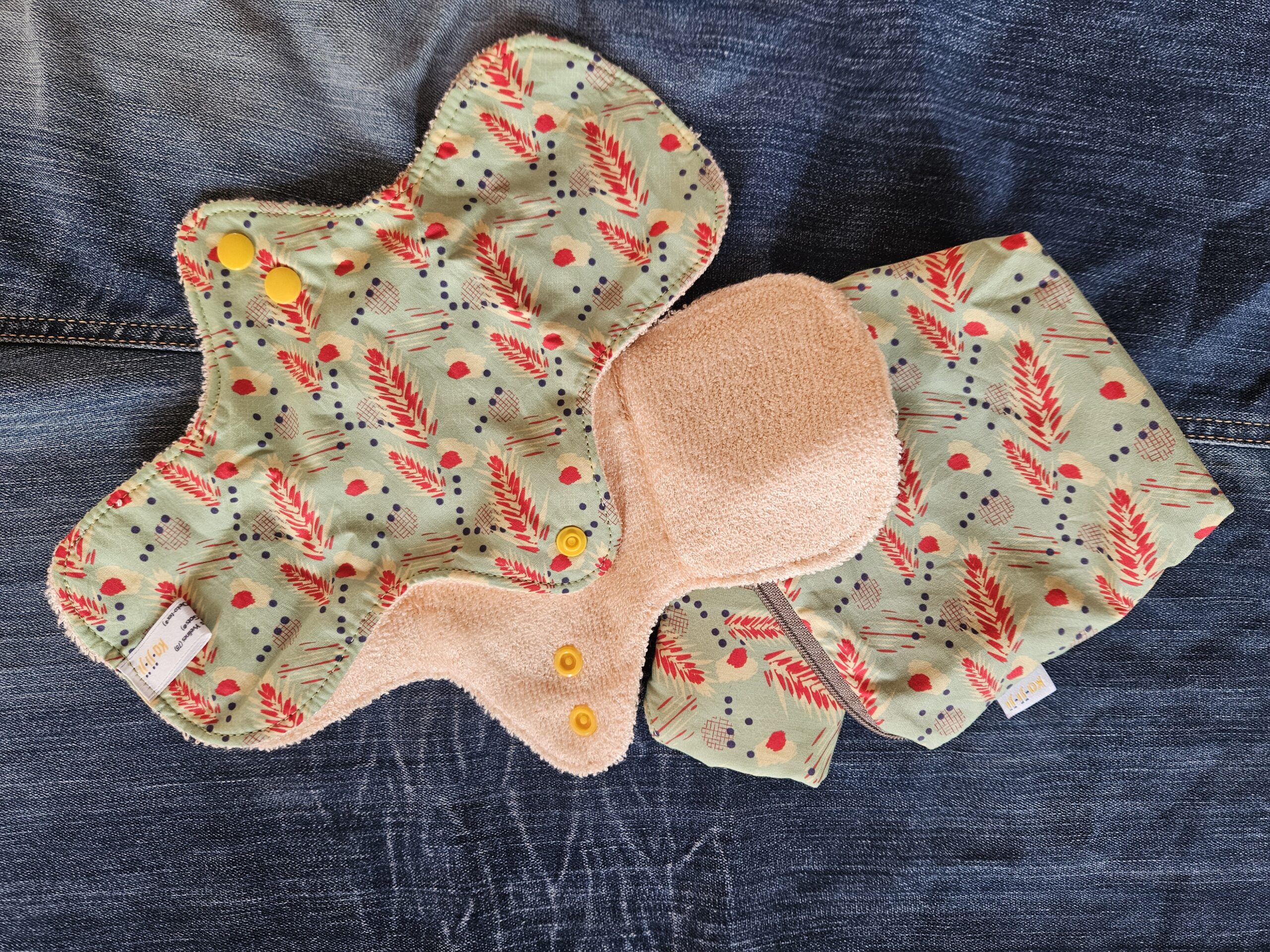 Accessoire zéro déchet de la savonnerie artisanale Sabuni & Cie. Serviettes menstruelles écologiques & solidaires. Fait en France. Protections hygiéniques KA.JI.JI sur fond bleu jeans.